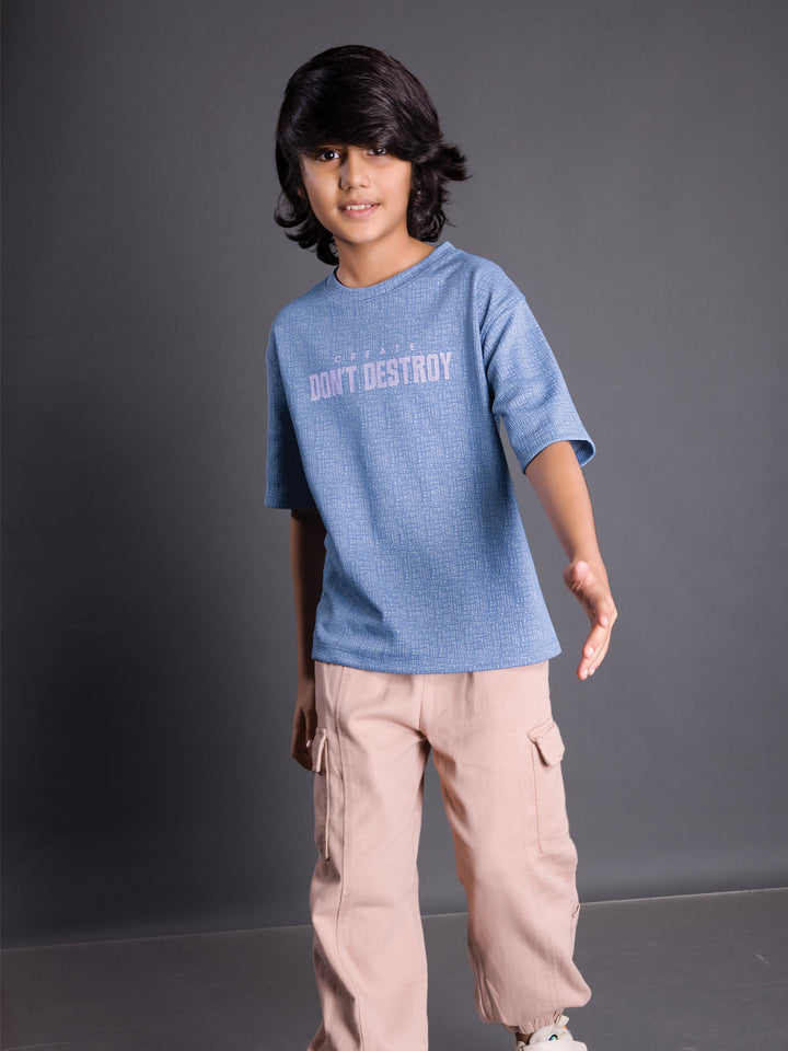 Boy wearing a printed drop shoulder round neck t-shirt with a relaxed fit