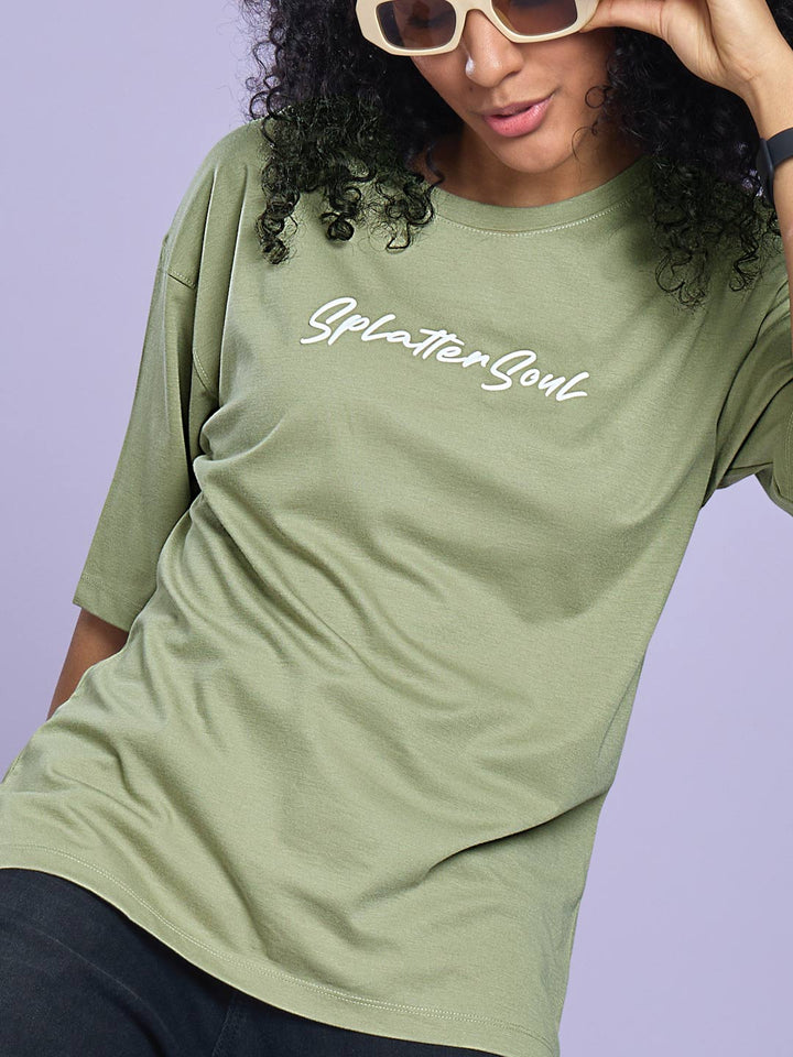 Person wearing a green t-shirt with 'Splatter Soul' text on a light purple background