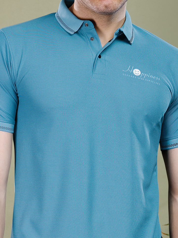 Teal polo shirt with a logo on a neutral background
