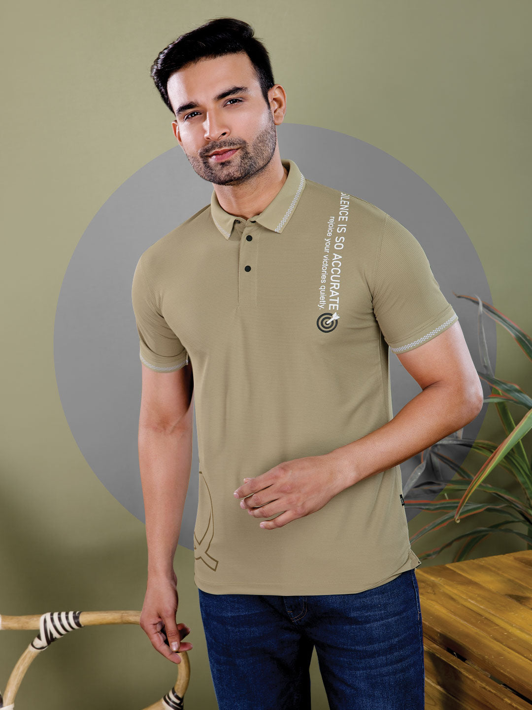 Man wearing a beige polo shirt with text and logo, standing against a green background.