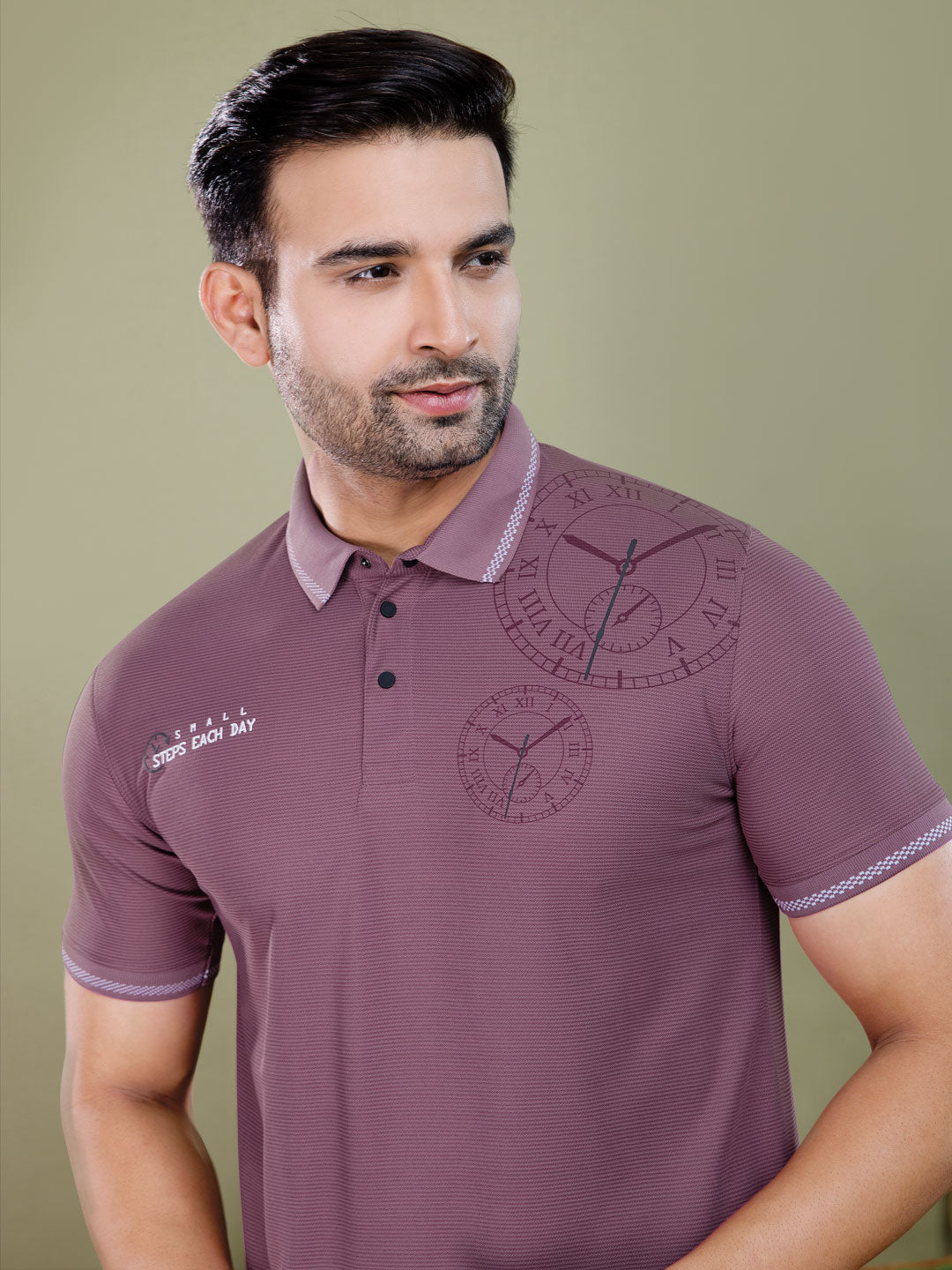 Man wearing a maroon polo shirt with clock designs on a green background