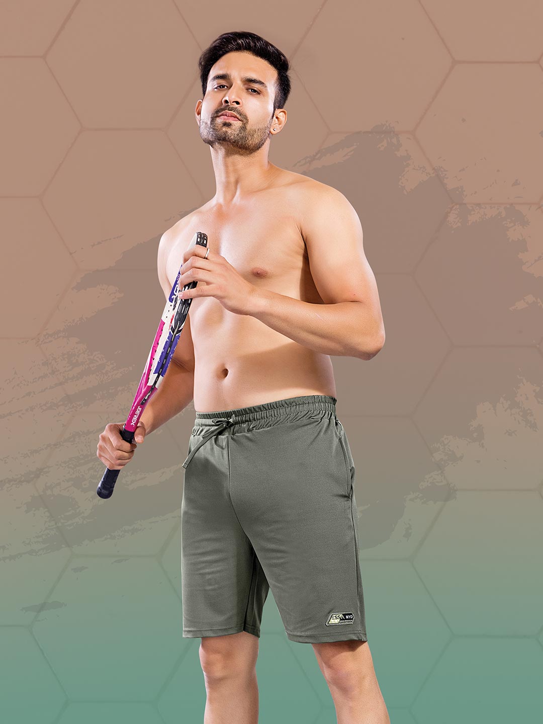 Man holding a tennis racket wearing gray shorts on a gradient background