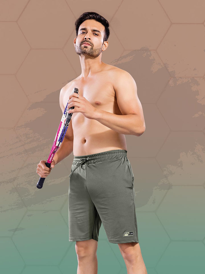 Man holding a tennis racket wearing gray shorts on a gradient background