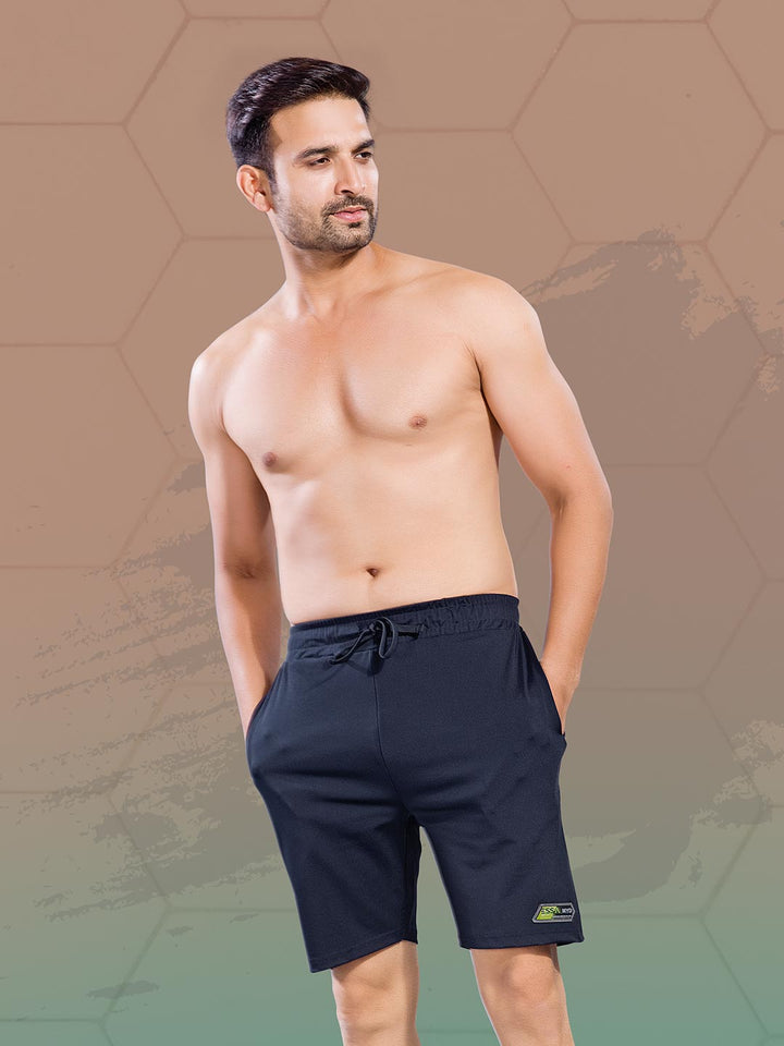 Man wearing navy blue shorts against a geometric patterned background