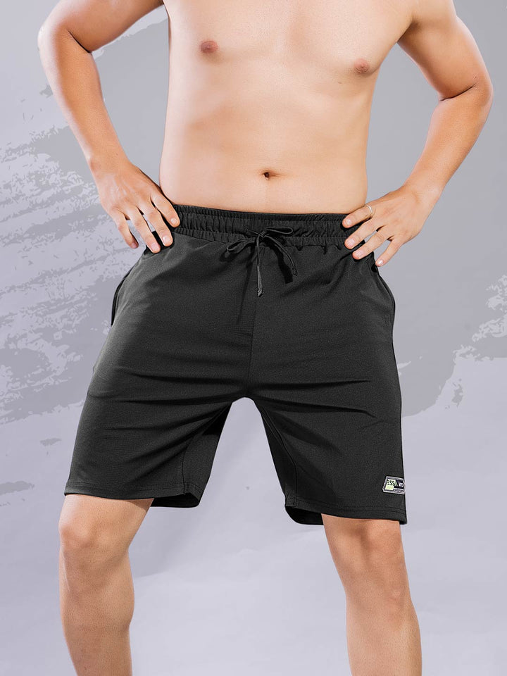 Person wearing black shorts with a gray background