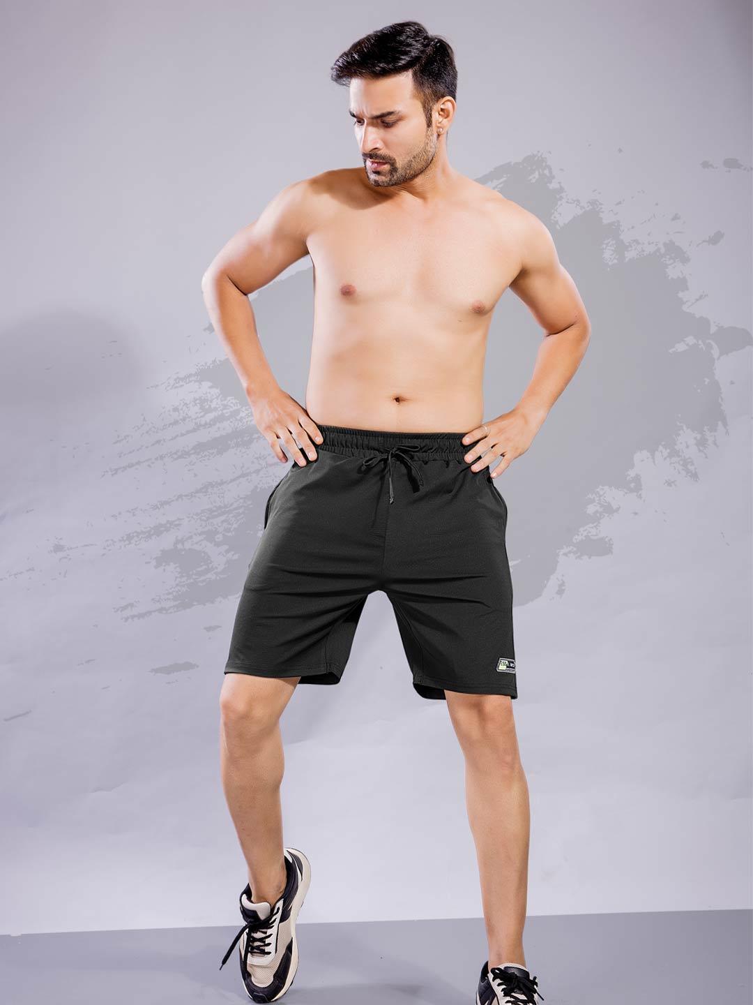 Man wearing black athletic shorts against a gray background