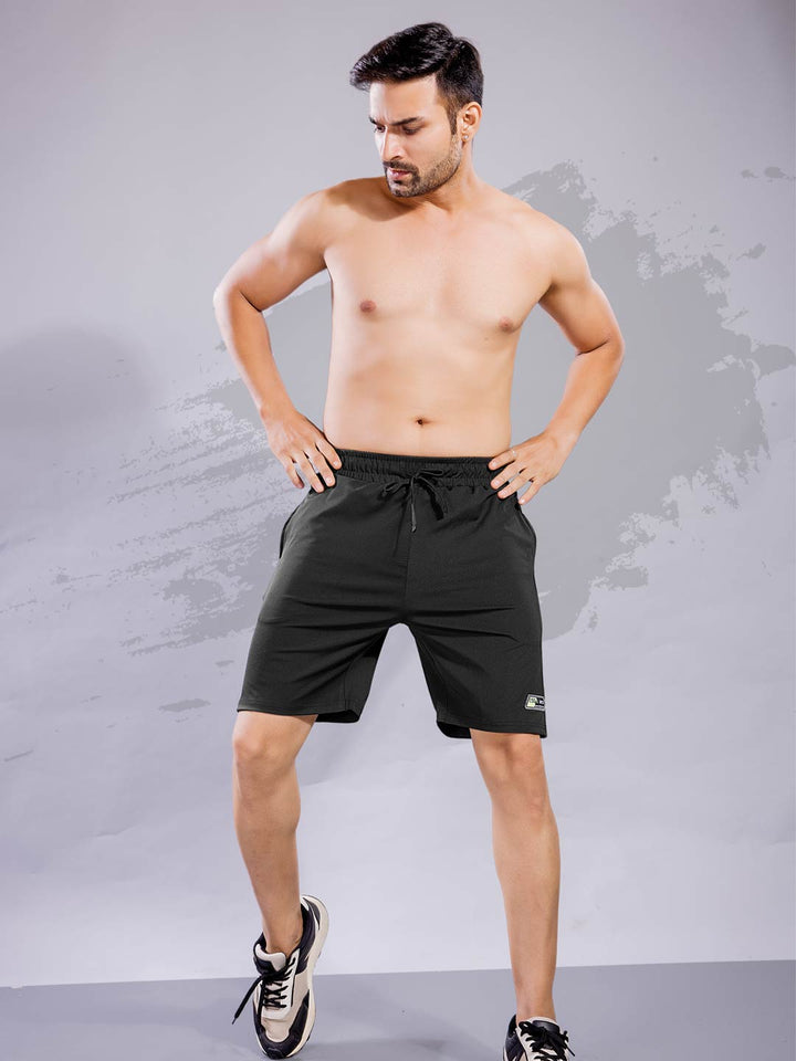 Man wearing black athletic shorts against a gray background