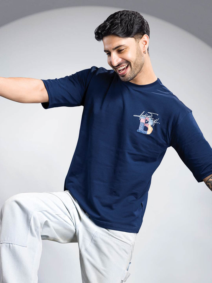 Man wearing a navy blue t-shirt with a logo on a gray background