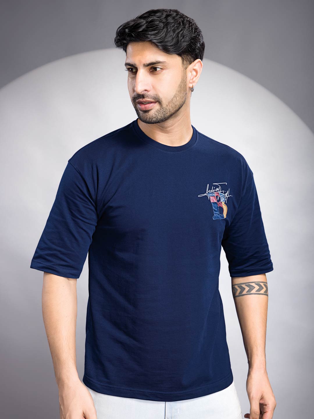 Man wearing a navy blue t-shirt with a logo on a gray background