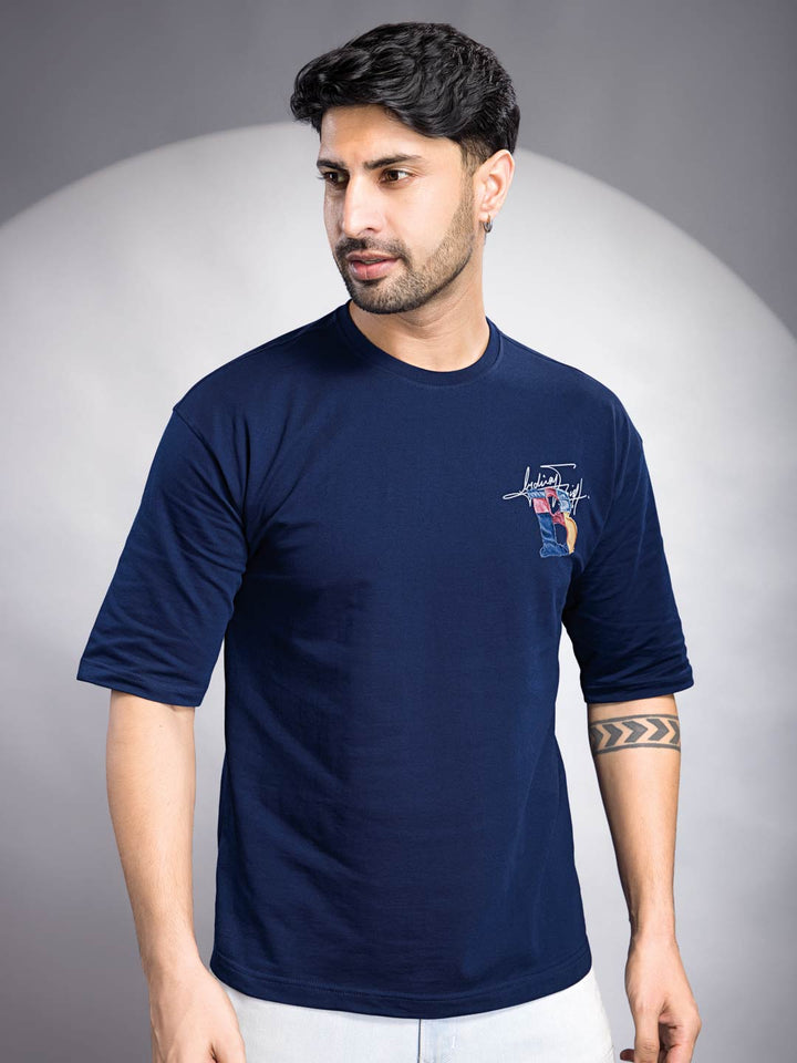 Man wearing a navy blue t-shirt with a logo on a gray background