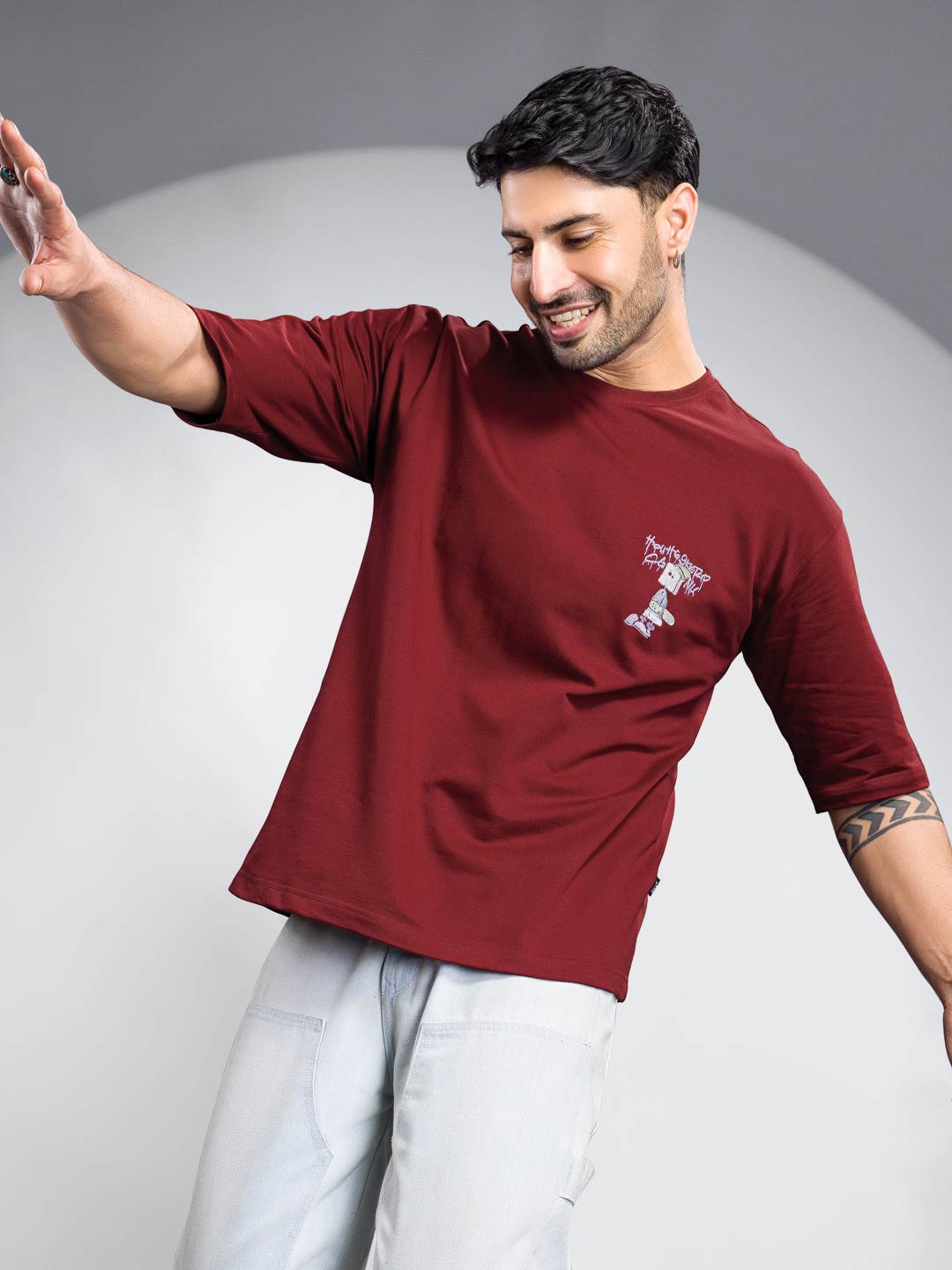 Man wearing a maroon t-shirt with a logo on a gray background