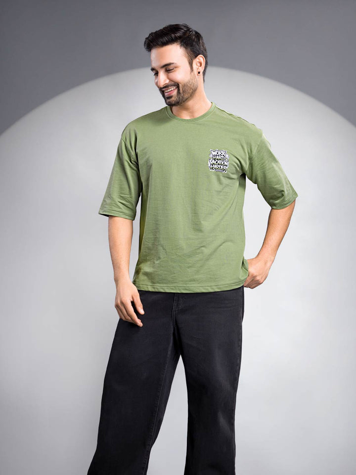 Man wearing a green t-shirt with text on a gray background
