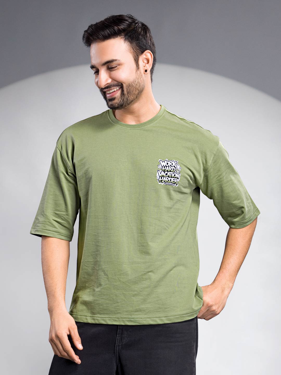 Man wearing a green t-shirt with a logo on a gray background