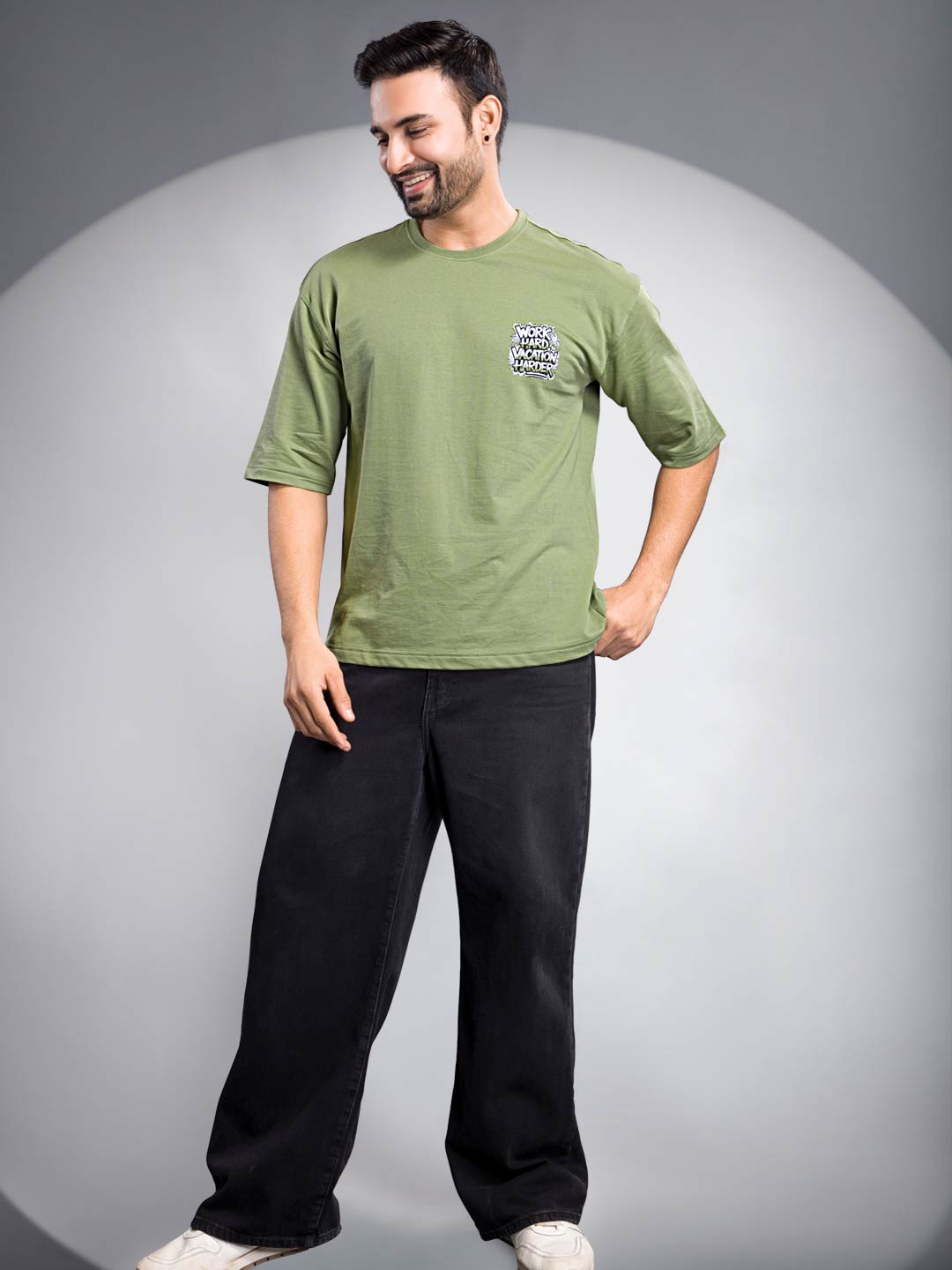 Man wearing a green t-shirt and black pants on a gray background
