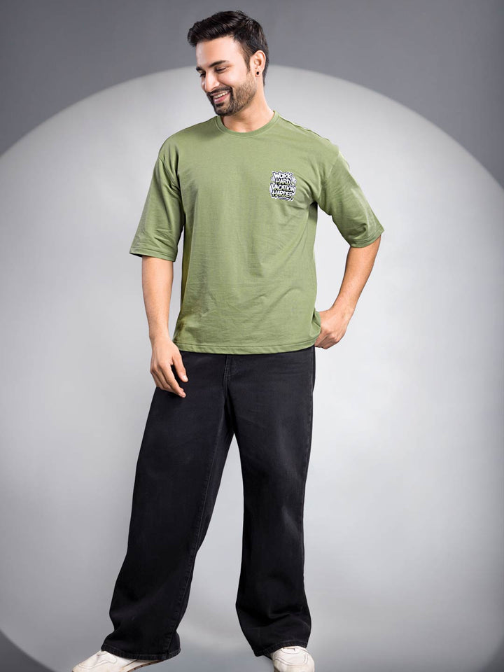 Man wearing a green t-shirt and black pants on a gray background