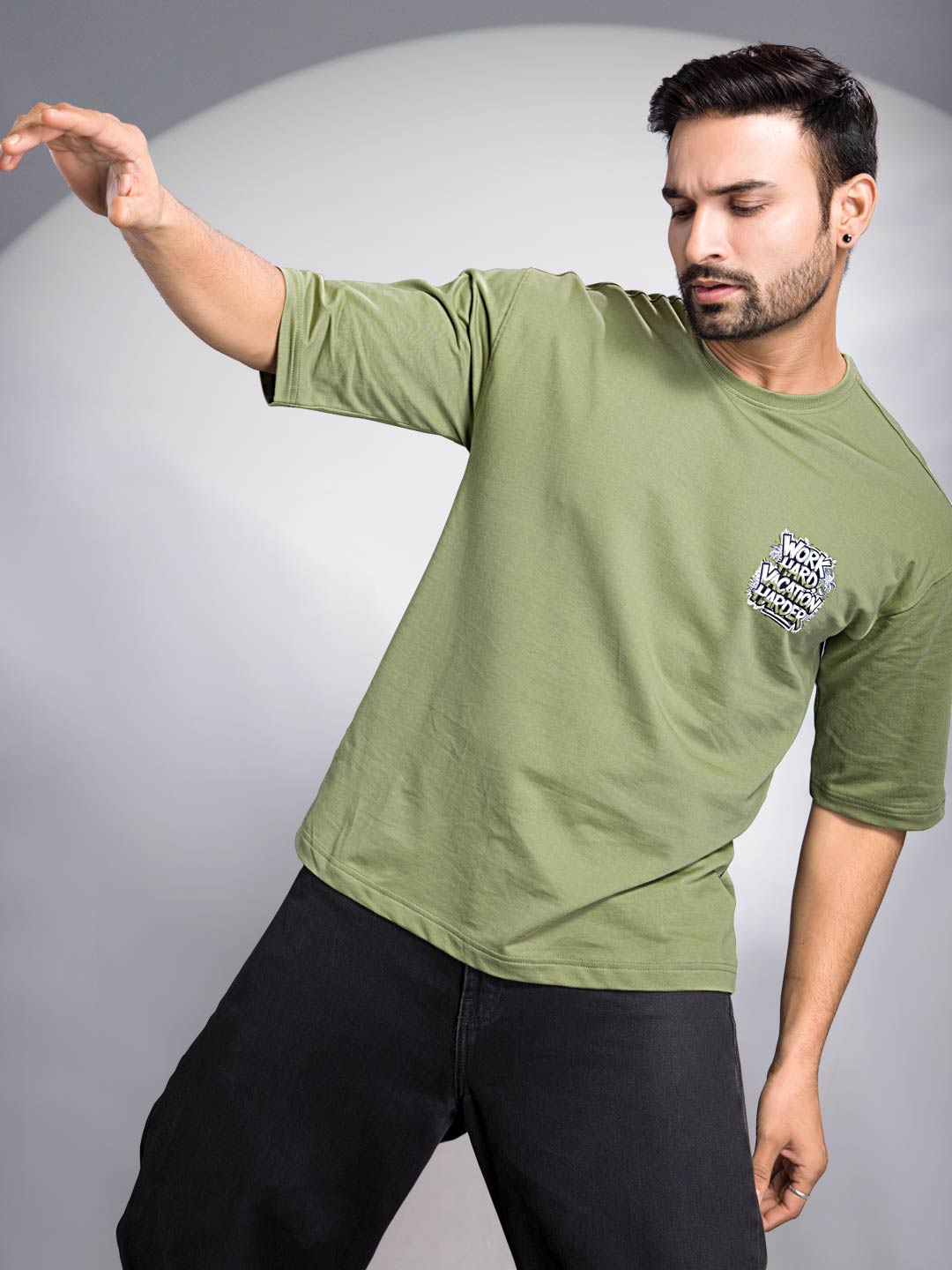 Man wearing a green t-shirt with a logo on a gray background