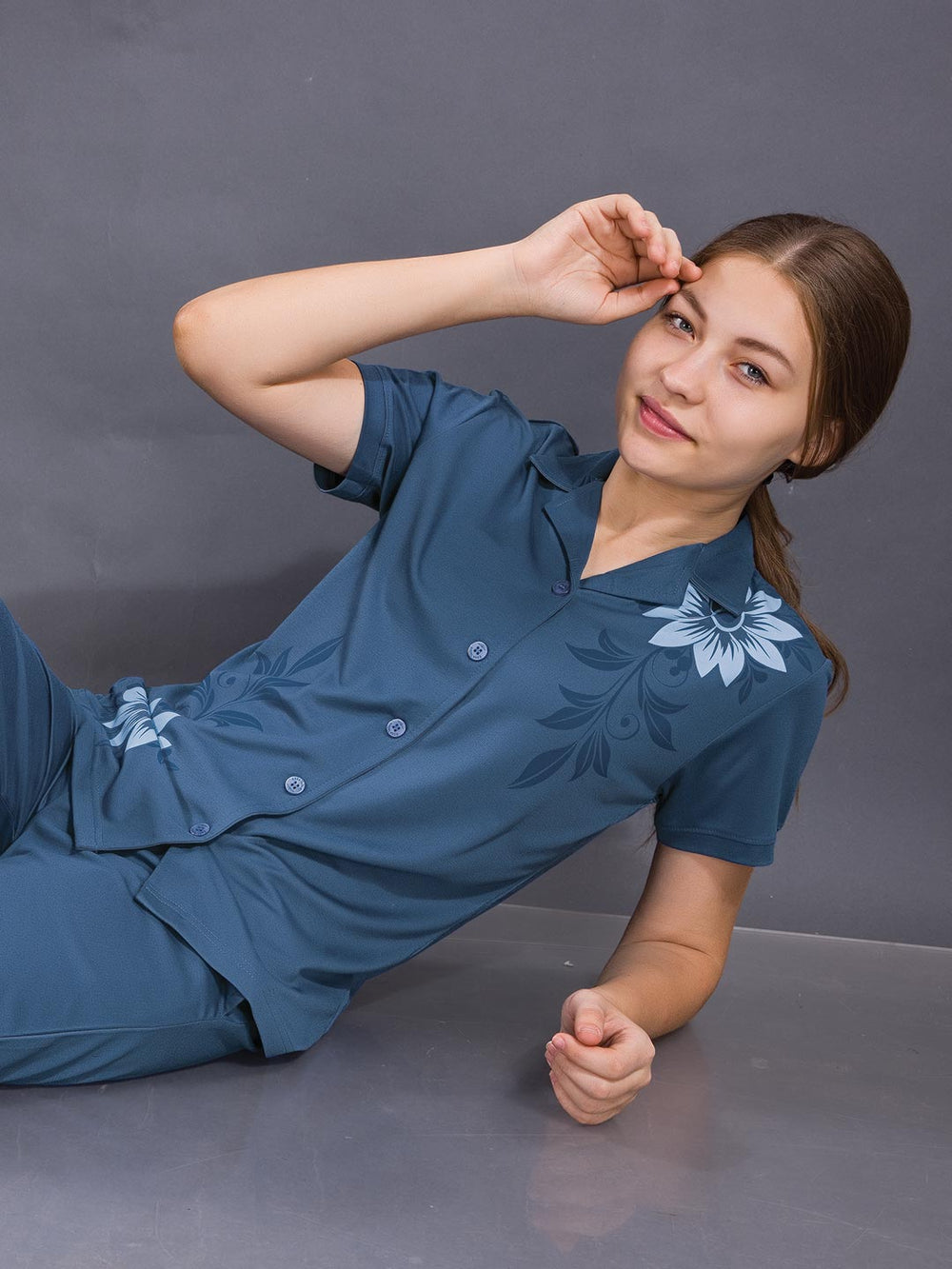 Woman wearing a blue outfit with floral patterns on a gray background