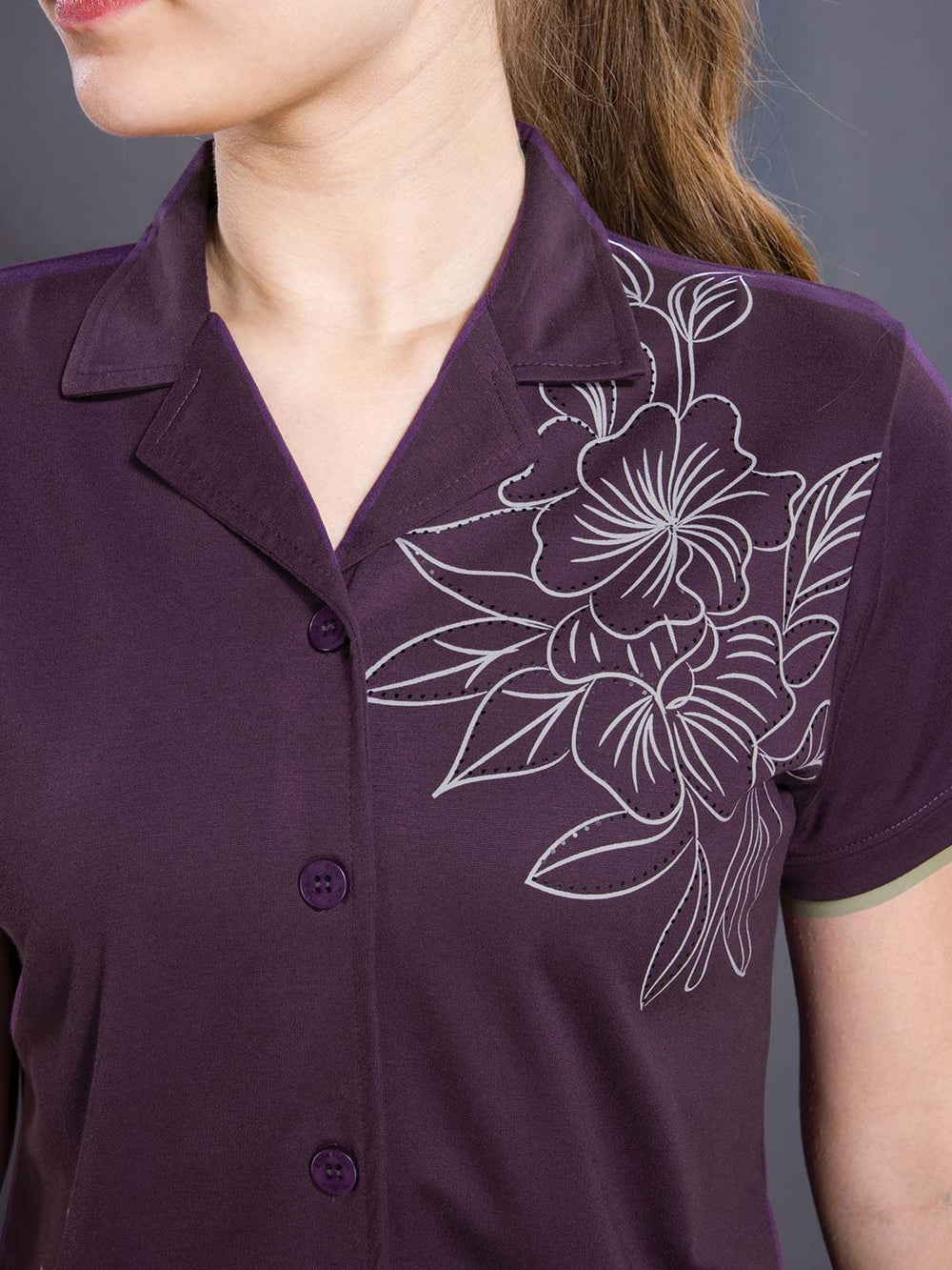 Purple shirt with white floral embroidery on a plain background