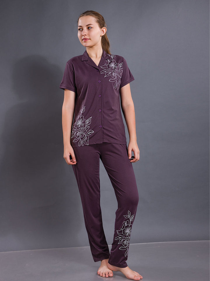 Woman wearing a purple pajama set with floral embroidery against a gray background