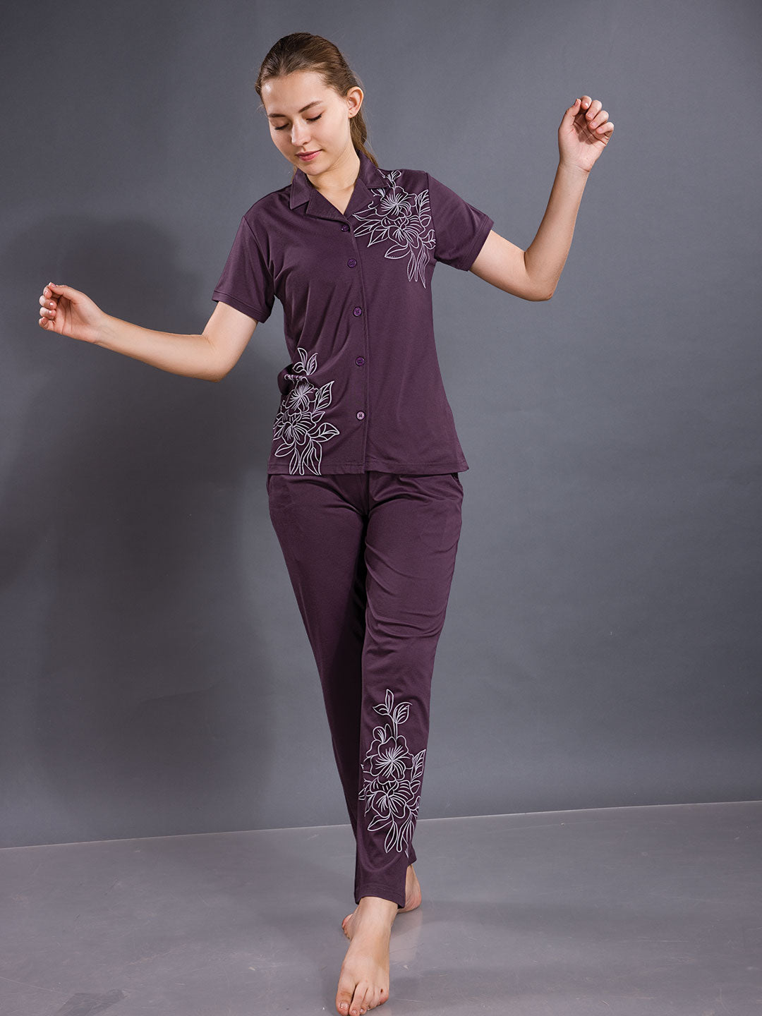 Woman wearing a purple outfit with floral embroidery on a gray background