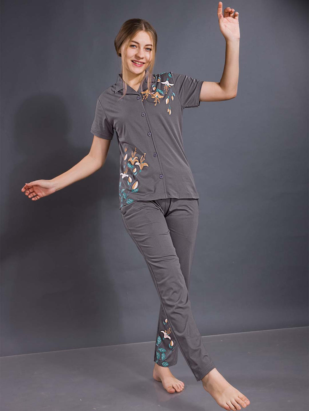 Woman wearing a gray pajama set with floral patterns on a dark background