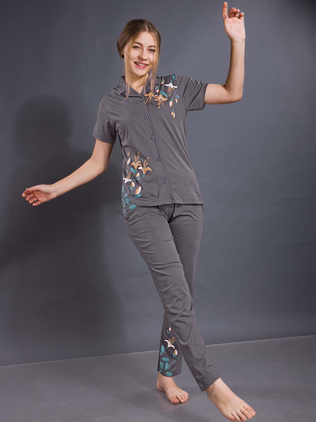 Woman wearing a gray pajama set with floral patterns on a dark background