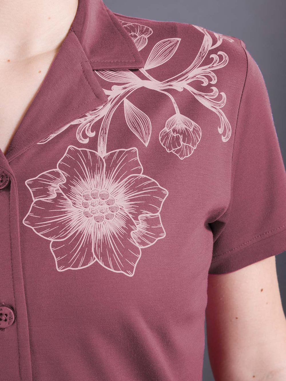 Maroon shirt with white floral design on a gray background