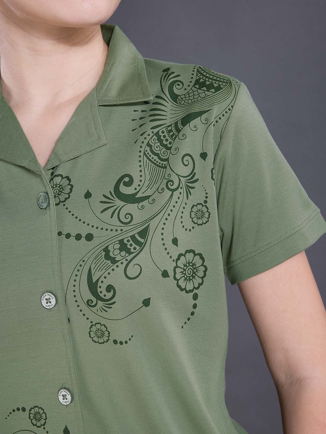 Green shirt with intricate black floral patterns on a gray background