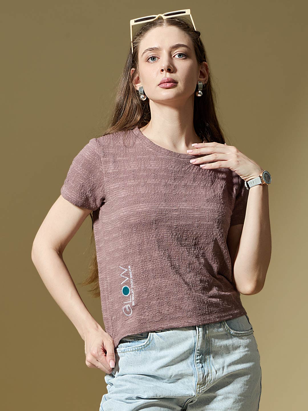 Woman wearing a maroon t-shirt with a logo on a beige background