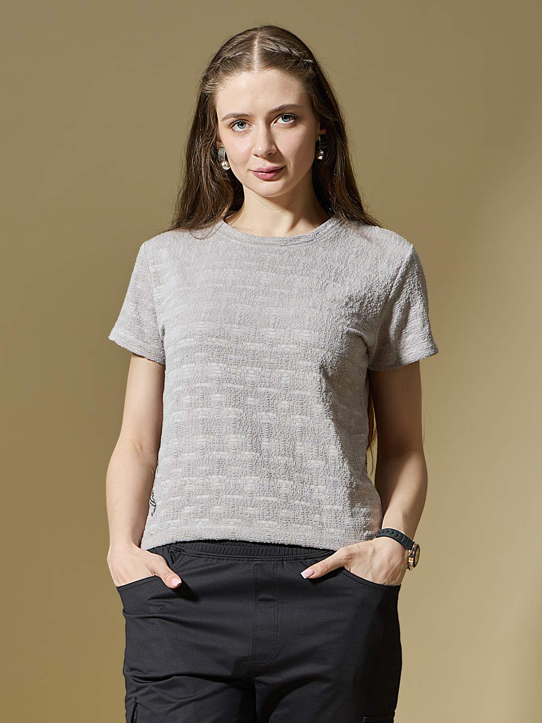 Woman wearing a textured gray t-shirt against a beige background