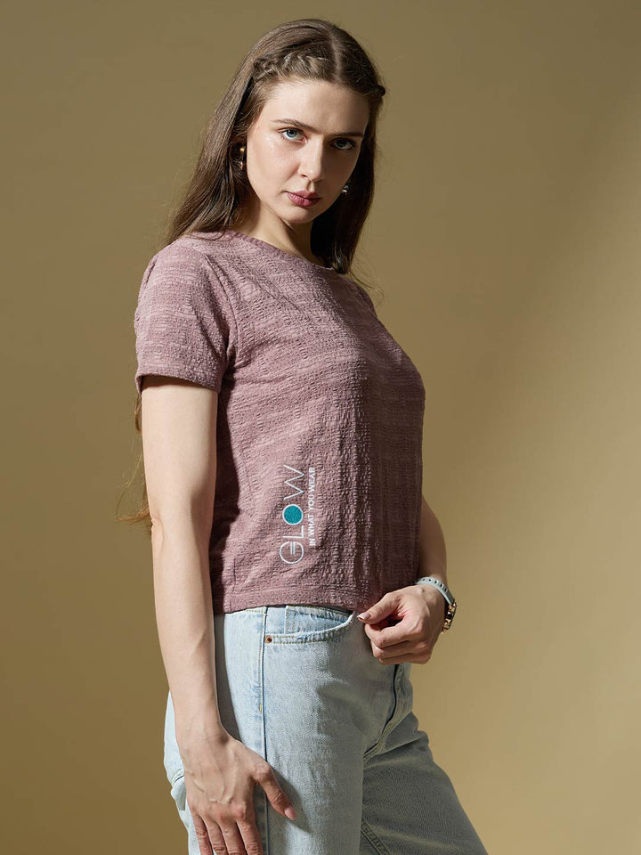 Woman wearing a maroon knitted sweater with a logo on a beige background