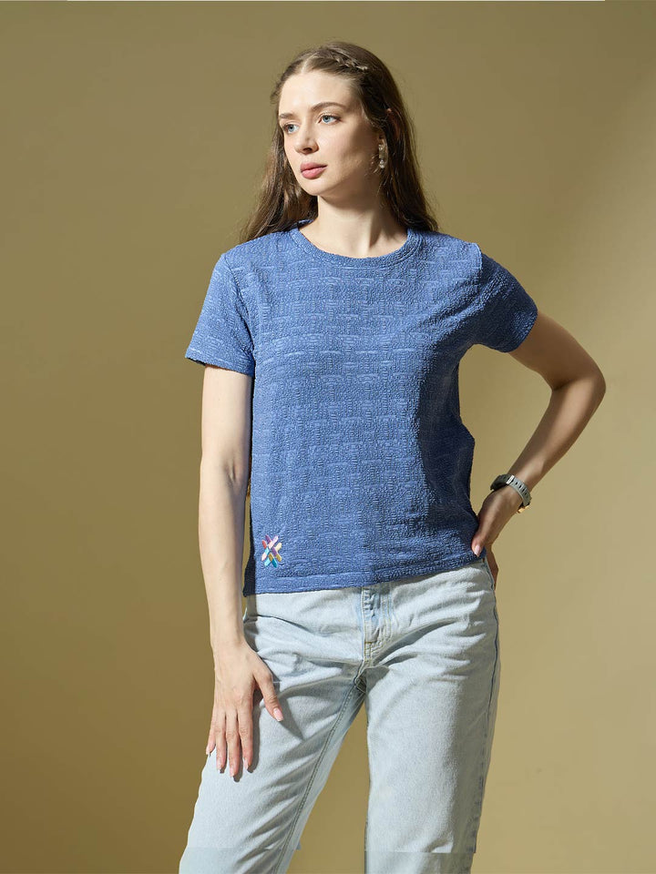Woman wearing a blue knitted shirt with a small design on a beige background