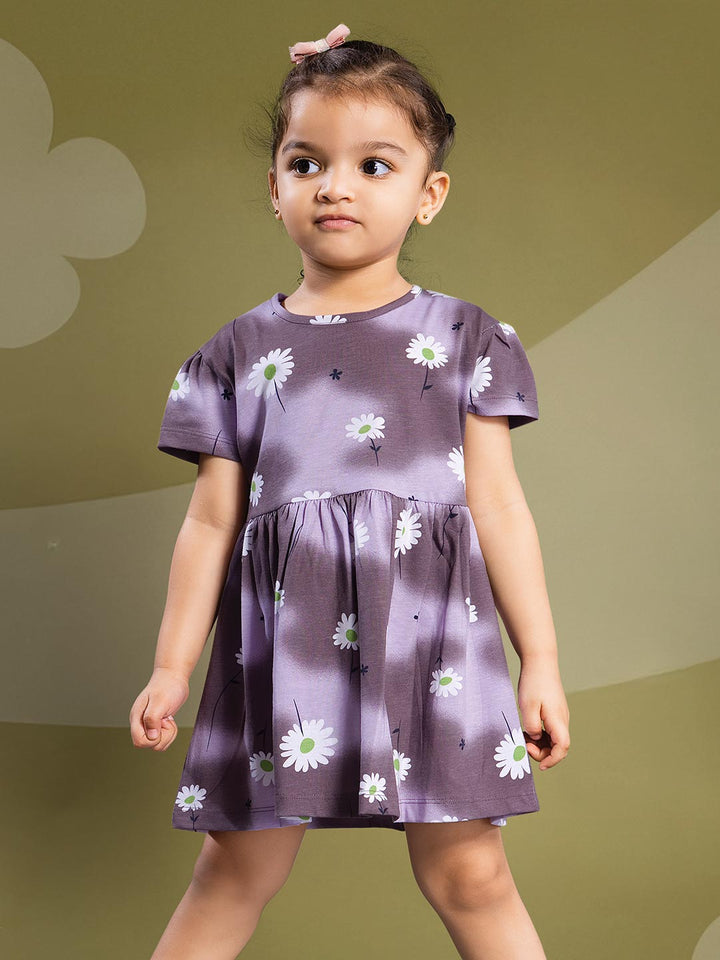 Young girl wearing a purple dress with white floral patterns on a green background