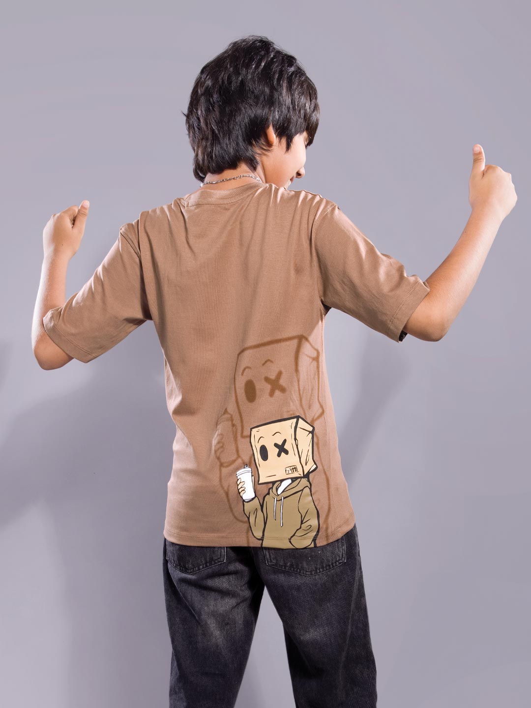 Person wearing a brown t-shirt with a cartoon character design on a plain background