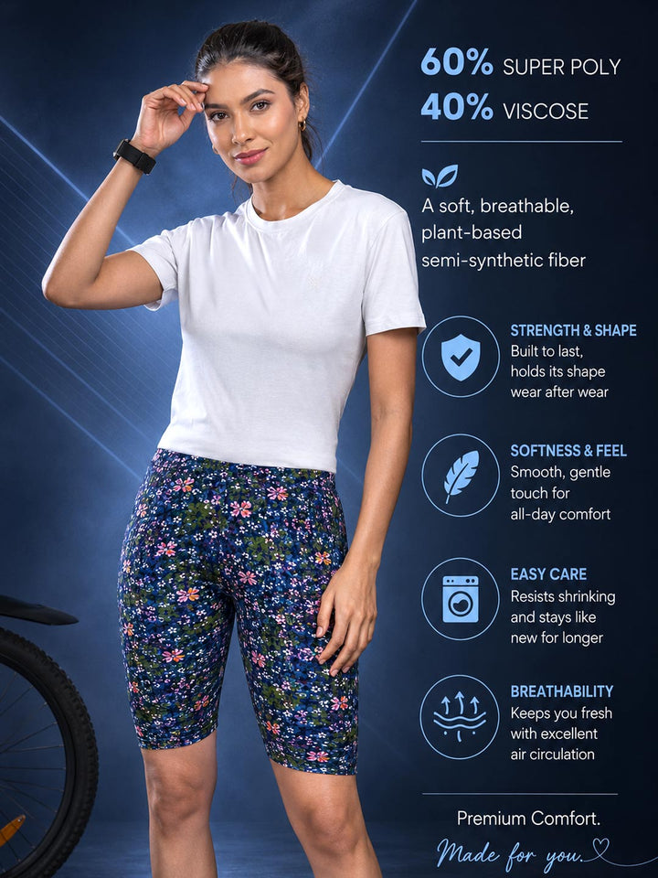 A woman modeling floral athletic shorts and a white t-shirt against a dark blue promotional background with product text and feature icons. The shorts have a navy base with pink, purple, and green floral pattern.