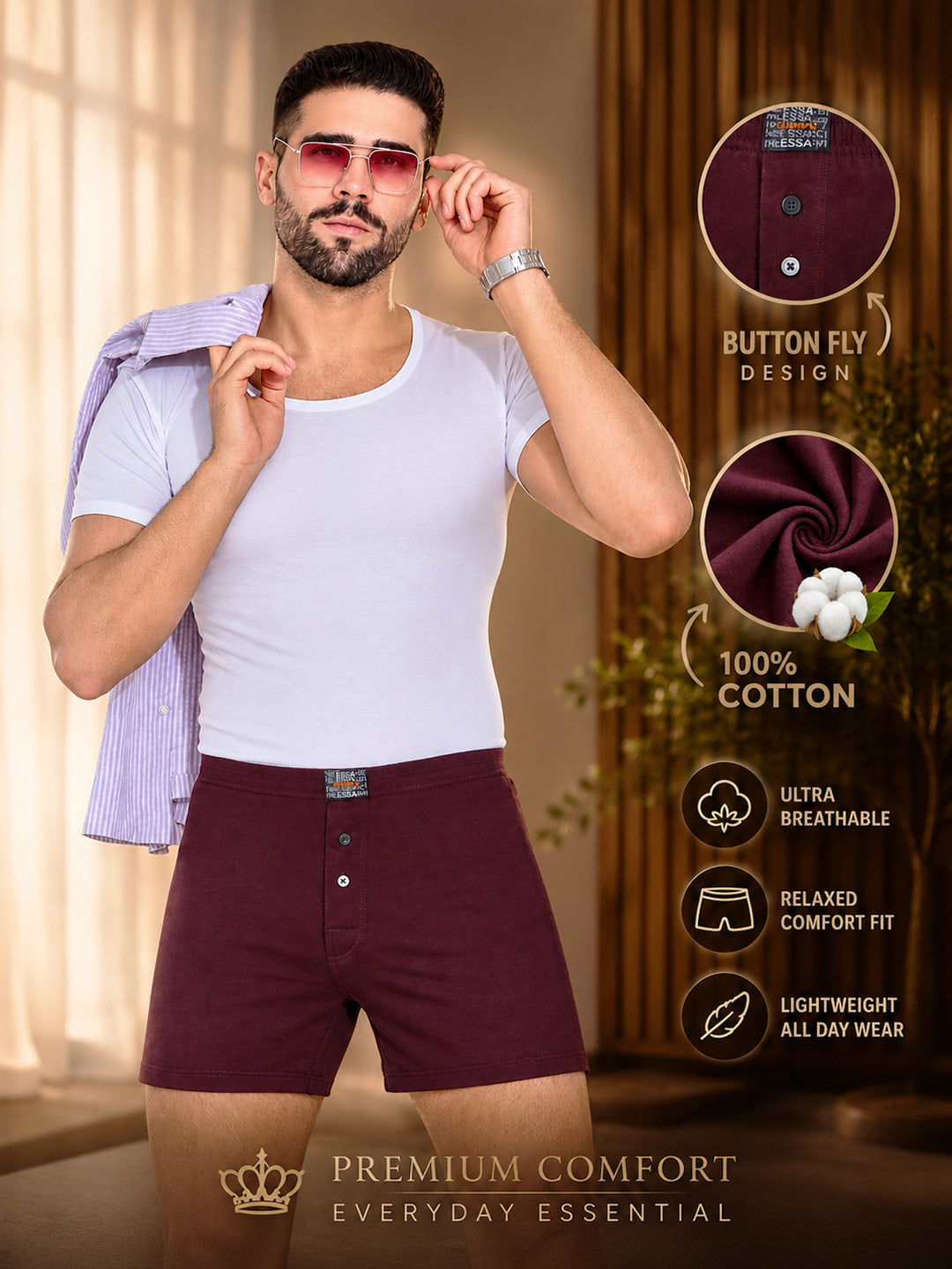 A man wearing burgundy cotton boxer briefs and a white t-shirt, with a light purple striped shirt draped over his shoulder, set against a warm indoor background. The image includes feature callouts on the right highlighting button fly design, 100% cotton, breathable fabric, relaxed comfort fit, and lightweight all-day wear. #color_dark-sienna