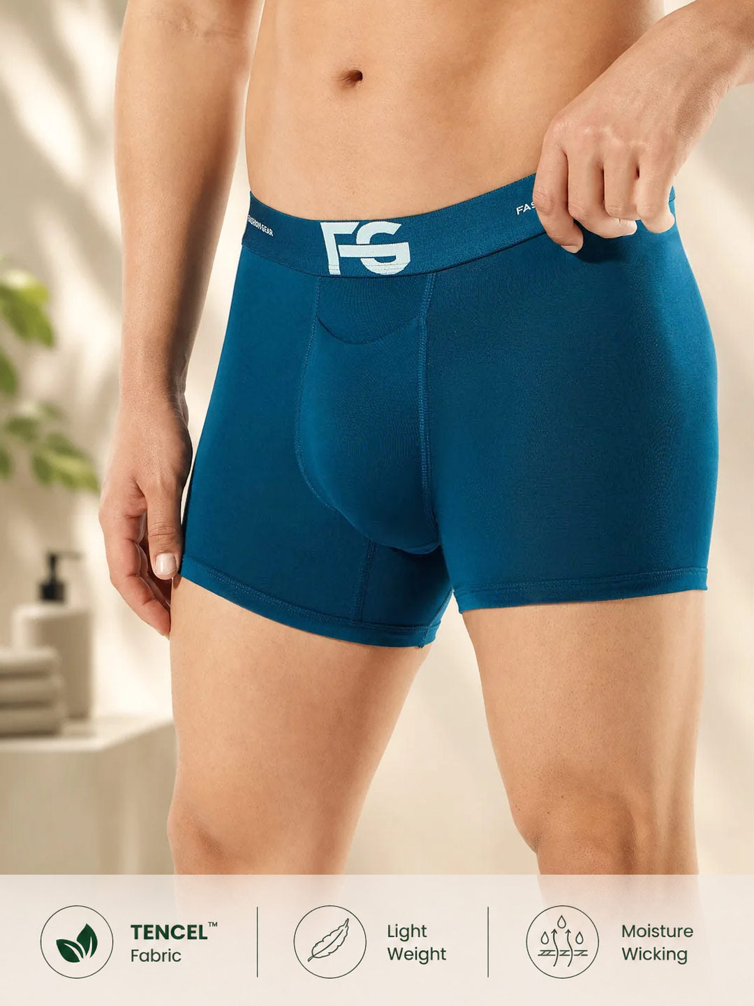A man wearing teal-blue boxer briefs with a white FG logo on the waistband. The image shows the lower torso and legs of the model, with a white banner at the bottom highlighting fabric and comfort features.#color_astronaut-blue