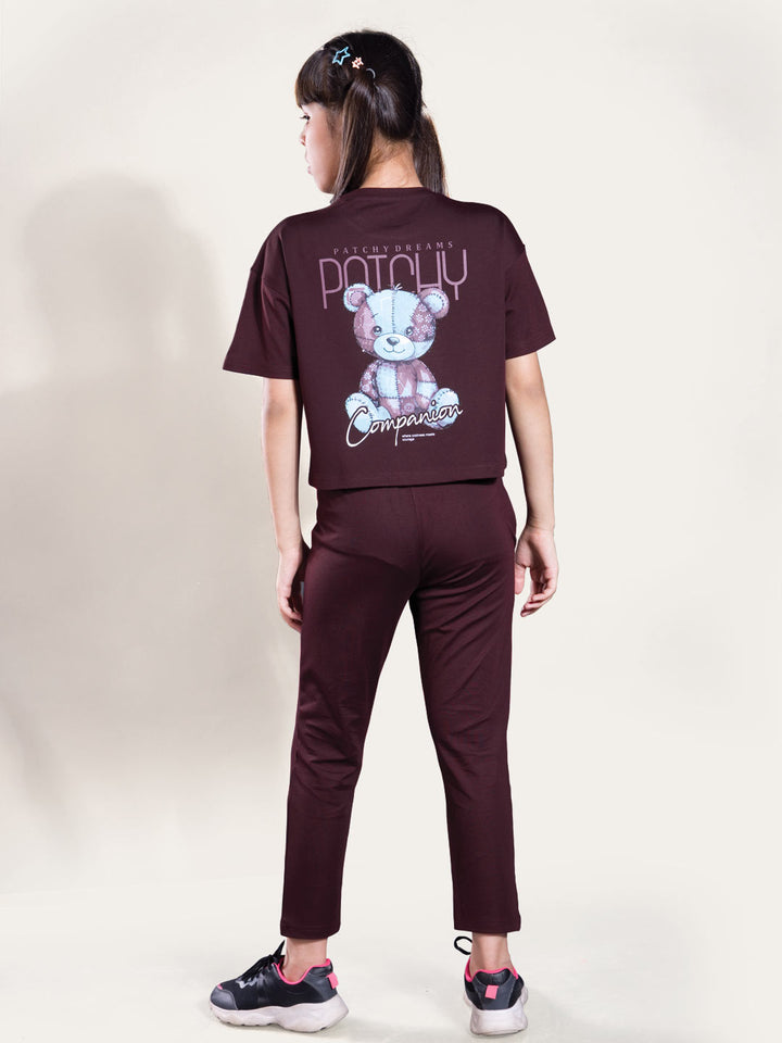 Person wearing a brown t-shirt with a bear graphic and text, standing against a white background