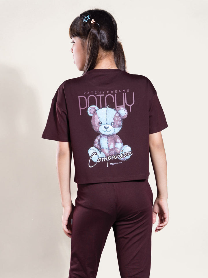 Person wearing a maroon outfit with a teddy bear graphic and text on the back.