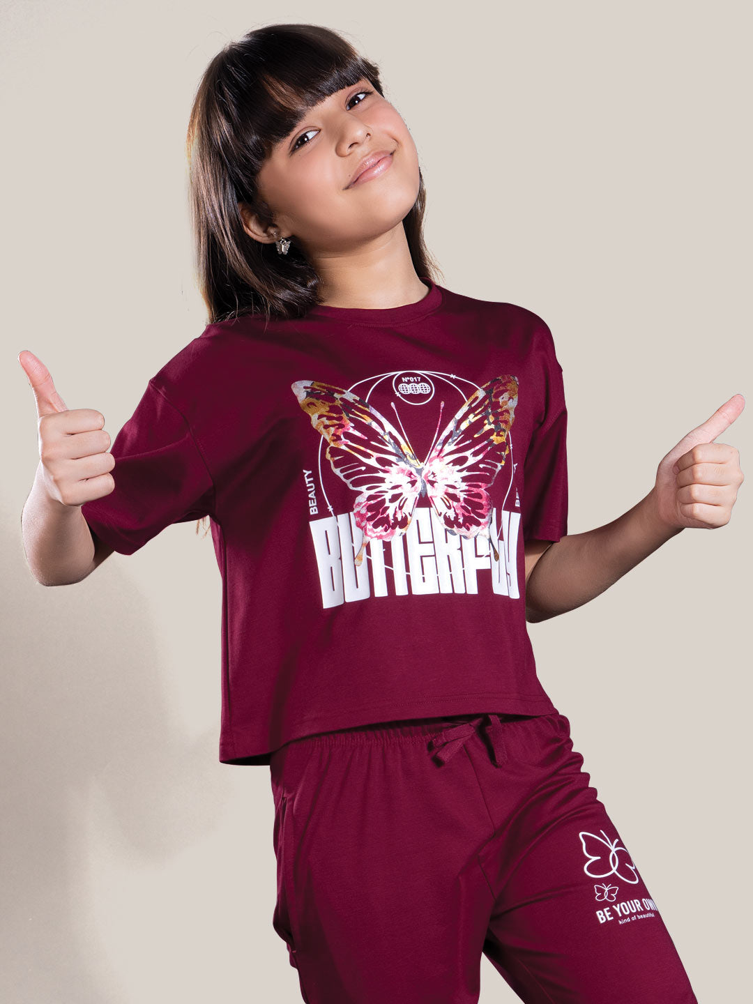 Child wearing a maroon outfit with butterfly design and text on a plain background