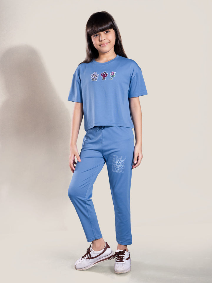 Person wearing a blue outfit with graphic designs on a plain background