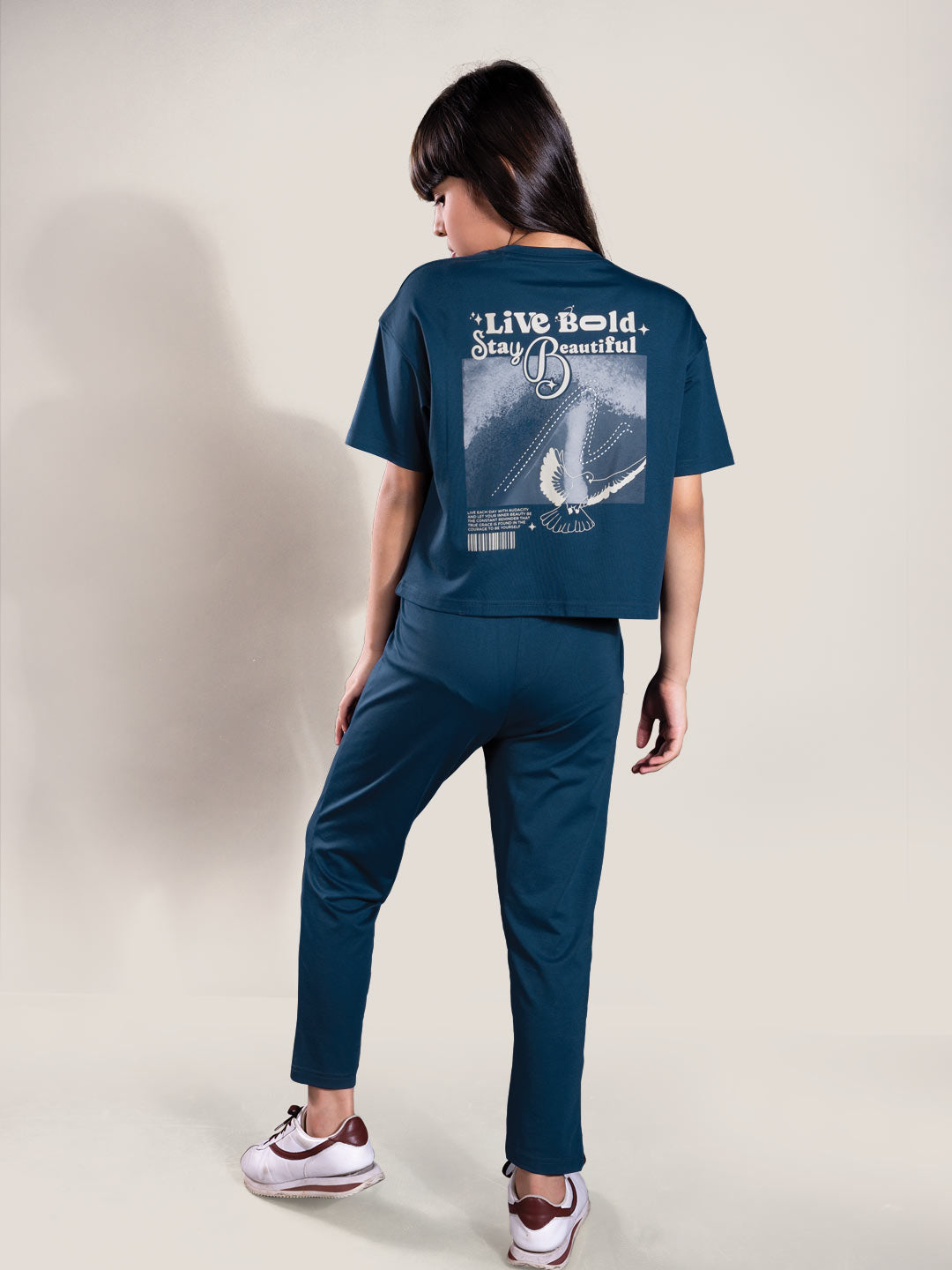 Person wearing a navy blue t-shirt and pants with a graphic design on the back, standing against a plain background.