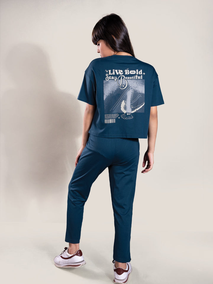 Person wearing a navy blue t-shirt and pants with a graphic design on the back, standing against a plain background.