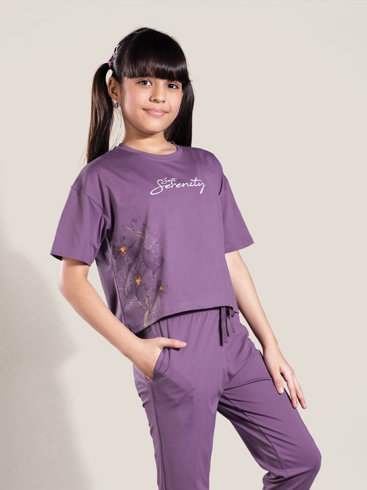 Young girl wearing a purple outfit with 'Serenity' text on a plain background