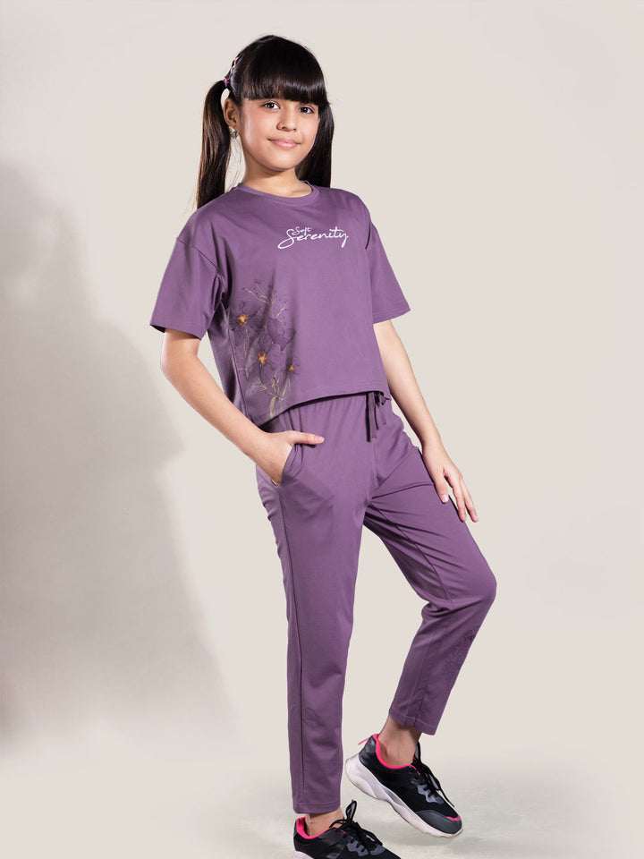 Young girl wearing a purple outfit with a logo on a plain background