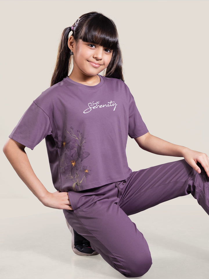 Young girl wearing a purple outfit with 'Serenity' text on a plain background