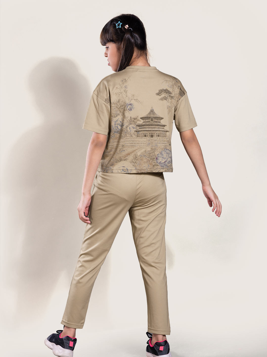 Person wearing a beige t-shirt and pants with a subtle pattern on a white background