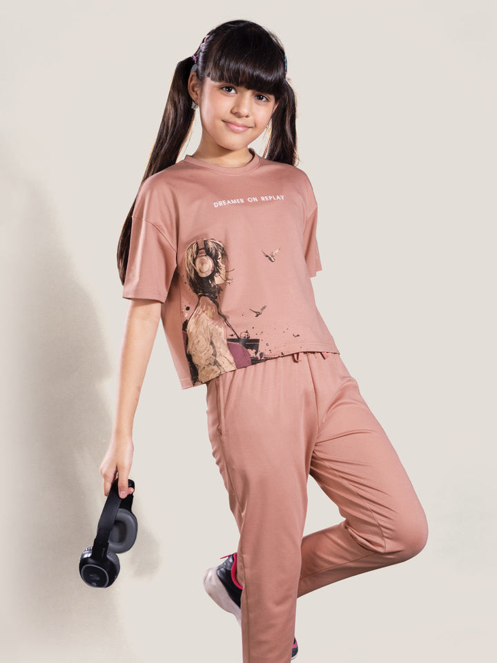 Young girl wearing a matching pink outfit with a graphic design on a plain background