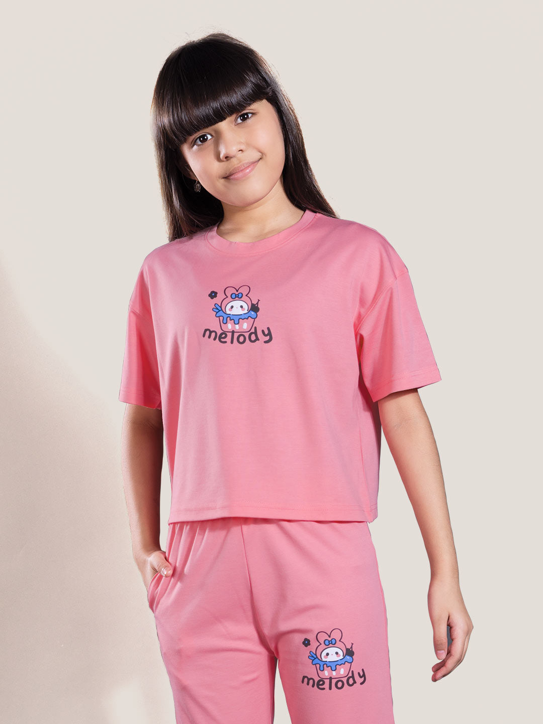 Young girl wearing a pink outfit with 'melody' branding on a plain background
