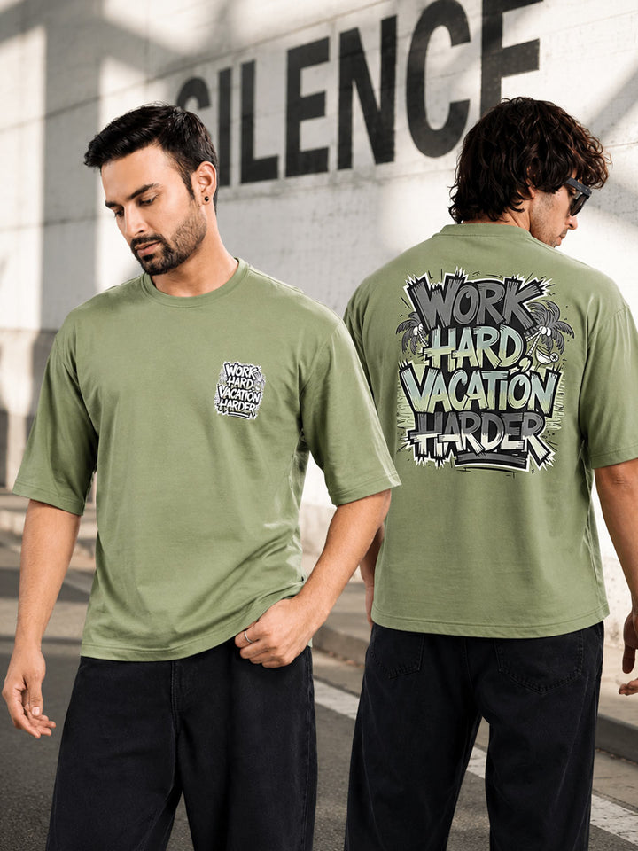 An olive green short-sleeve t-shirt shown on a male model from both the front and back. The front features a small graphic on the left chest, and the back features a large graphic with the text 'WORK HARD VACATION HARDER' in a distressed graffiti-style font.